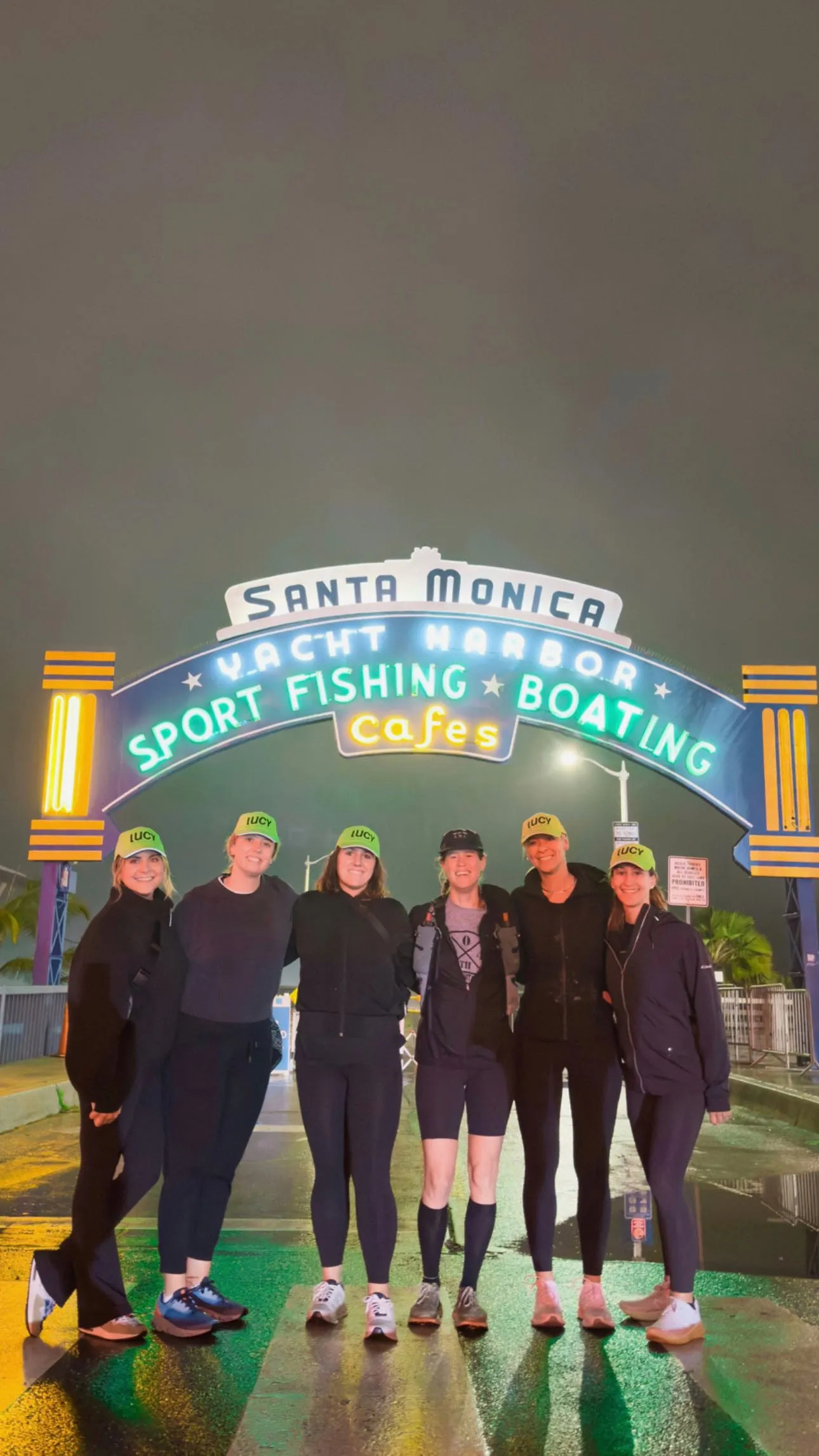 Lucy's crew posing under the lit Santa Monica Yacht Harbor arch before The Speed Project.