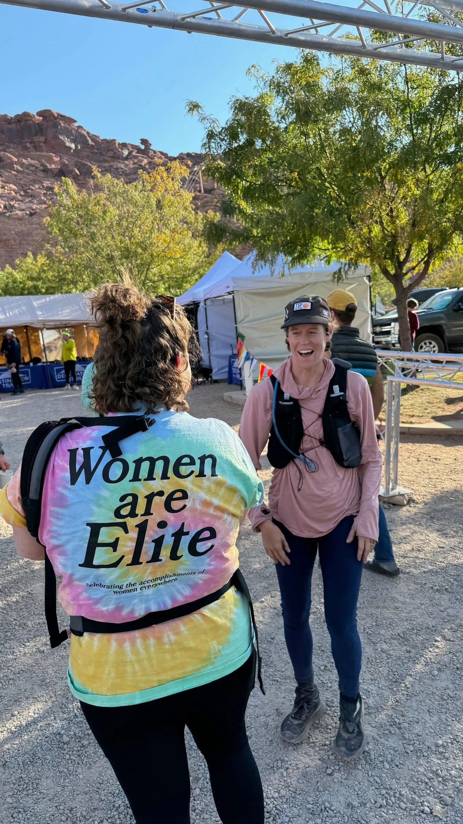 The back of a tie-dye shirt reading "Women are Elite" worn at a trail race.